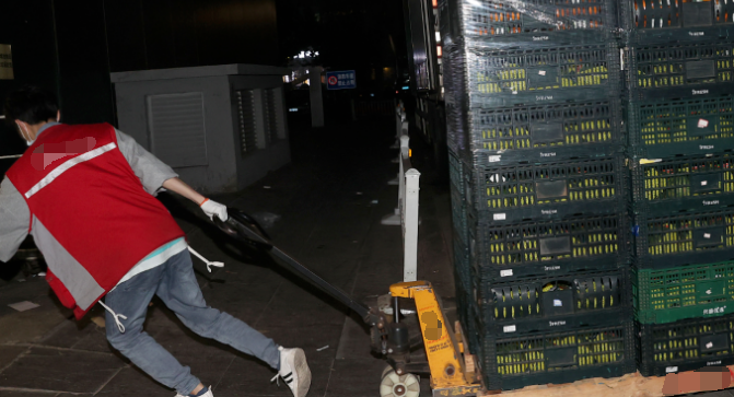 超市工作人員用地牛叉車(chē)卸貨拉運(yùn)貨物